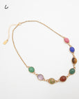 Scarab gemstone necklace with eight carved stone beetles in varied colors, including pink, blue, and green, photographed flat against a white background.
