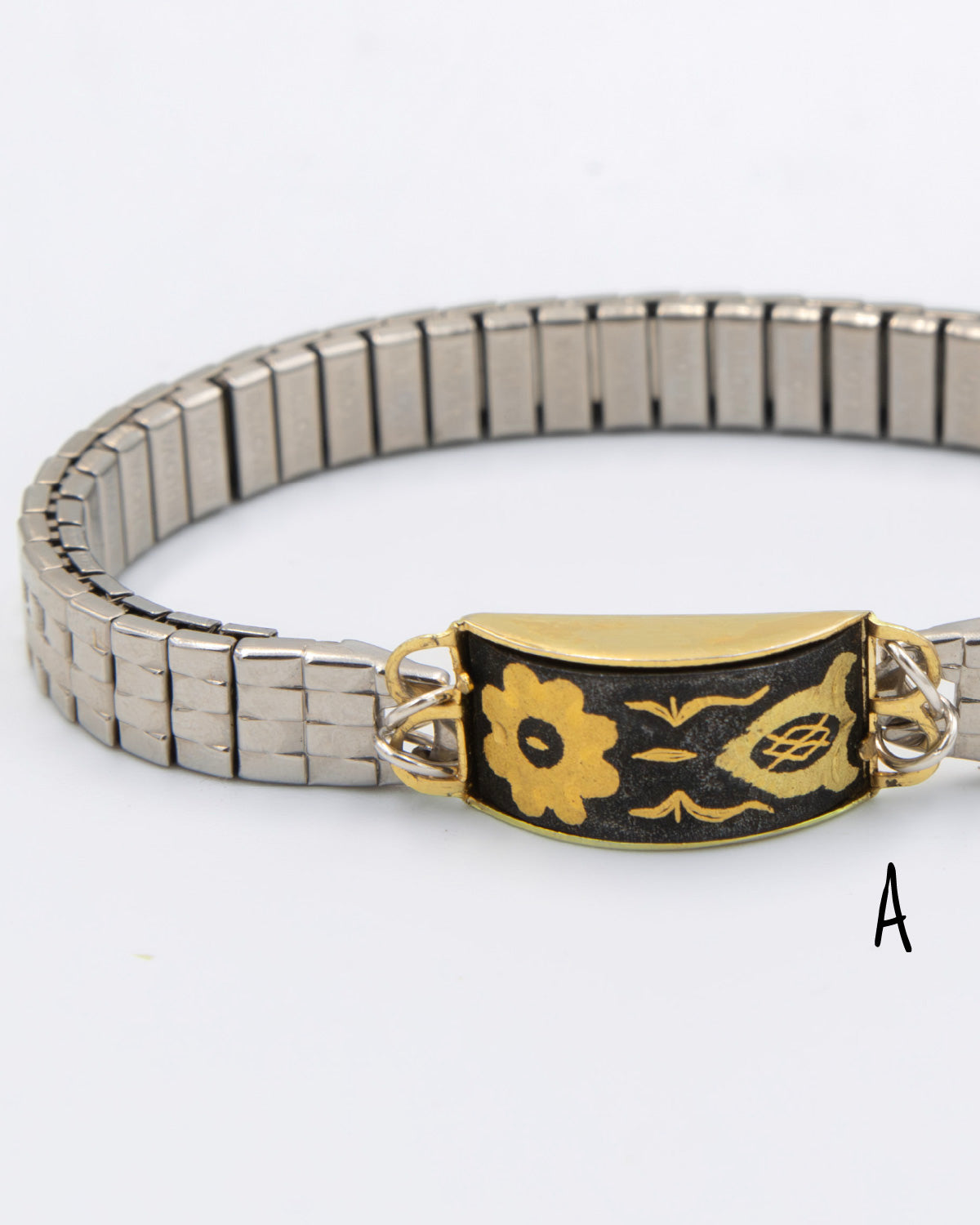 Silver bracelet with a decorative black and gold clasp on a white background