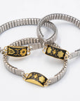 Silver bracelets with black and gold decorative elements on a white background