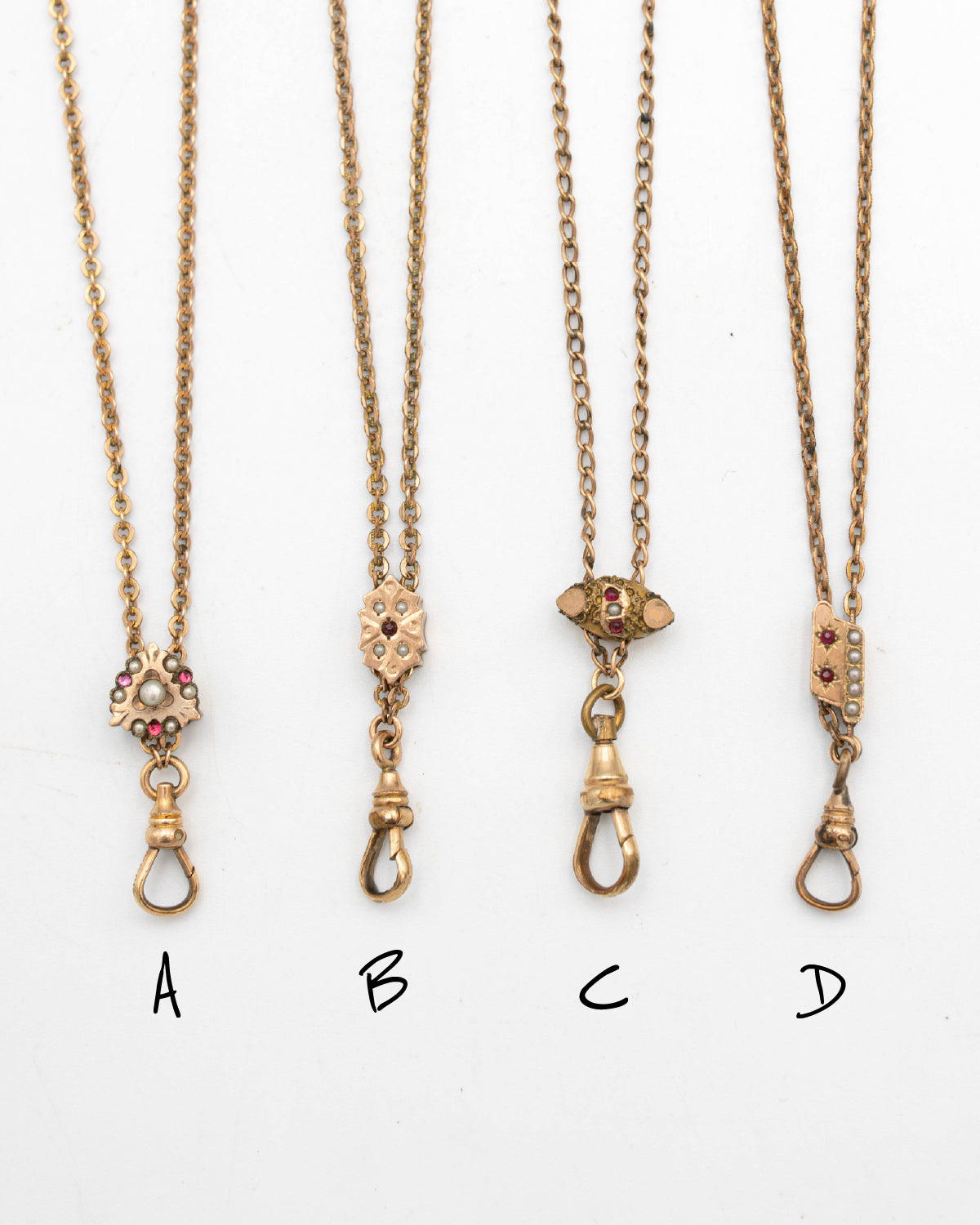 Four gold-filled Victorian-era chatelaine chain necklaces with small decorative pendants labeled A, B, C, and D on a plain white background.