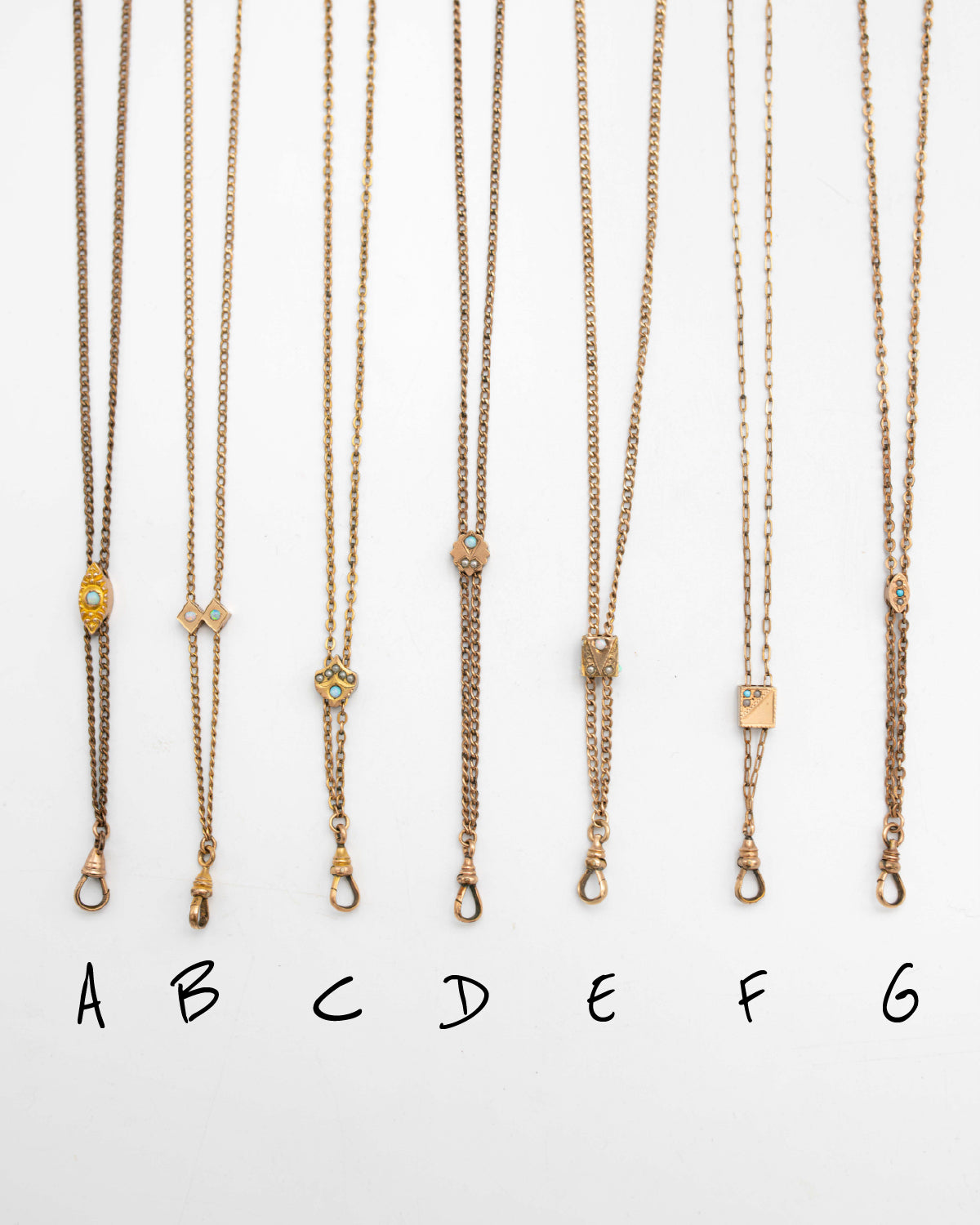 Six gold-filled Victorian-era chatelaine slider necklaces with different pendant styles are displayed vertically on a white background, labeled A through G below.
