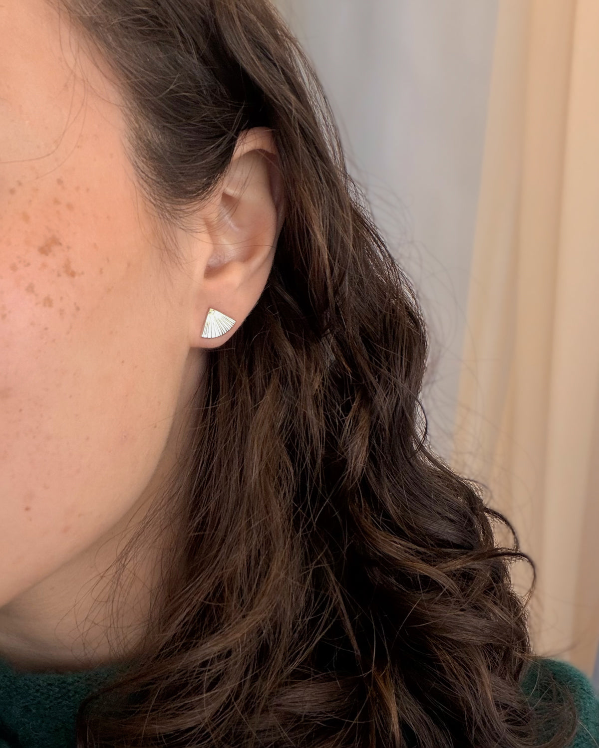 Close-up of a woman wearing silver fan-shaped earrings.