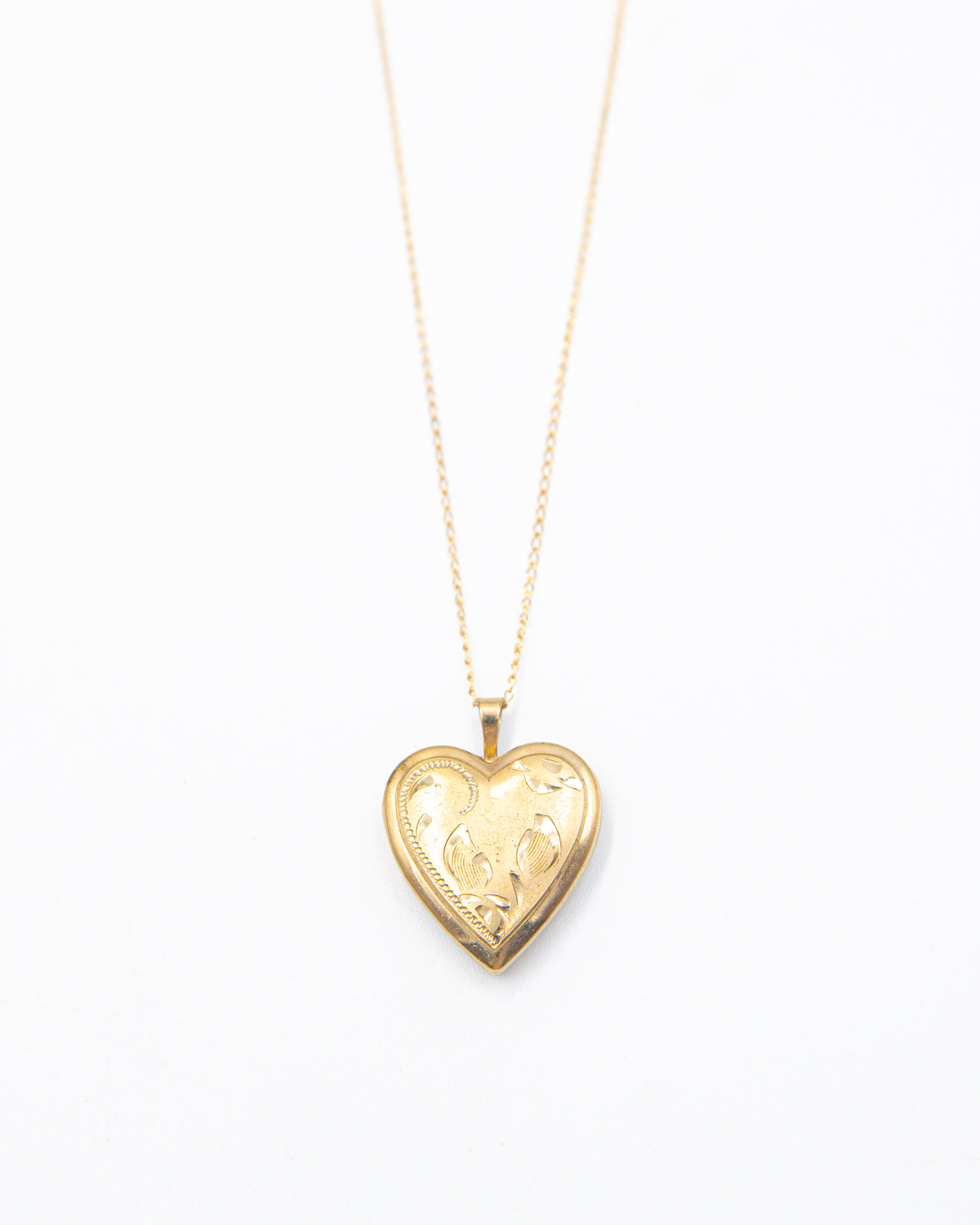 A gold heart-shaped locket pendant on a delicate gold chain, displayed against a clean white background.