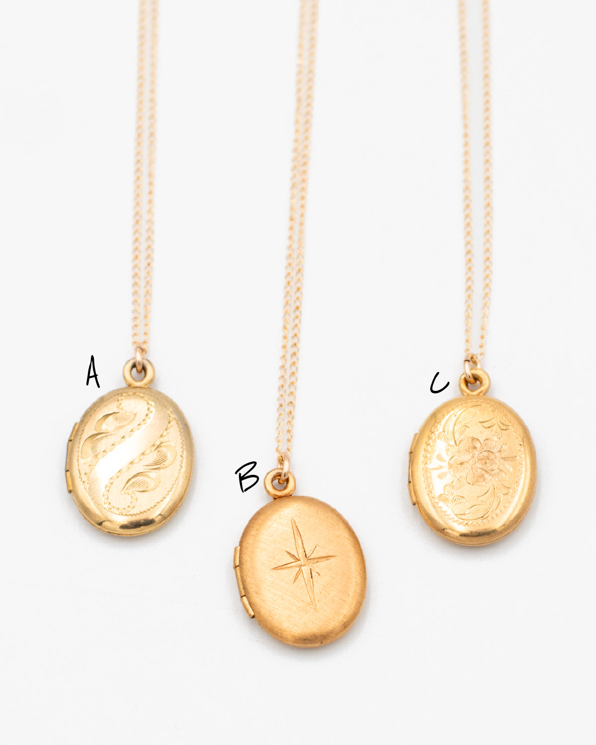 Three vintage oval gold lockets (A, B, C) featuring scroll, starburst, and floral engravings