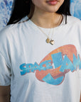 Woman wearing two engraved, vintage lockets (heart & oval) over a white graphic t-shrit. 