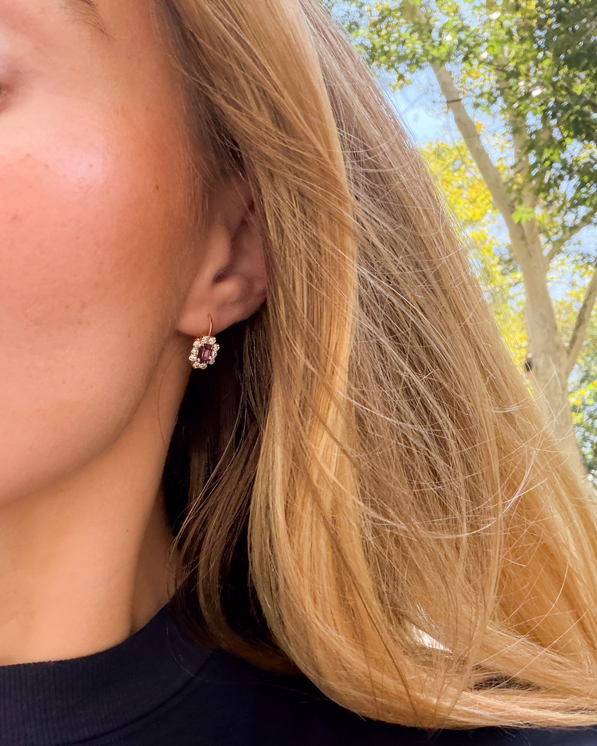 Close-up of an ear wearing a Violet Hour vintage earring with a faceted amethyst-colored stone