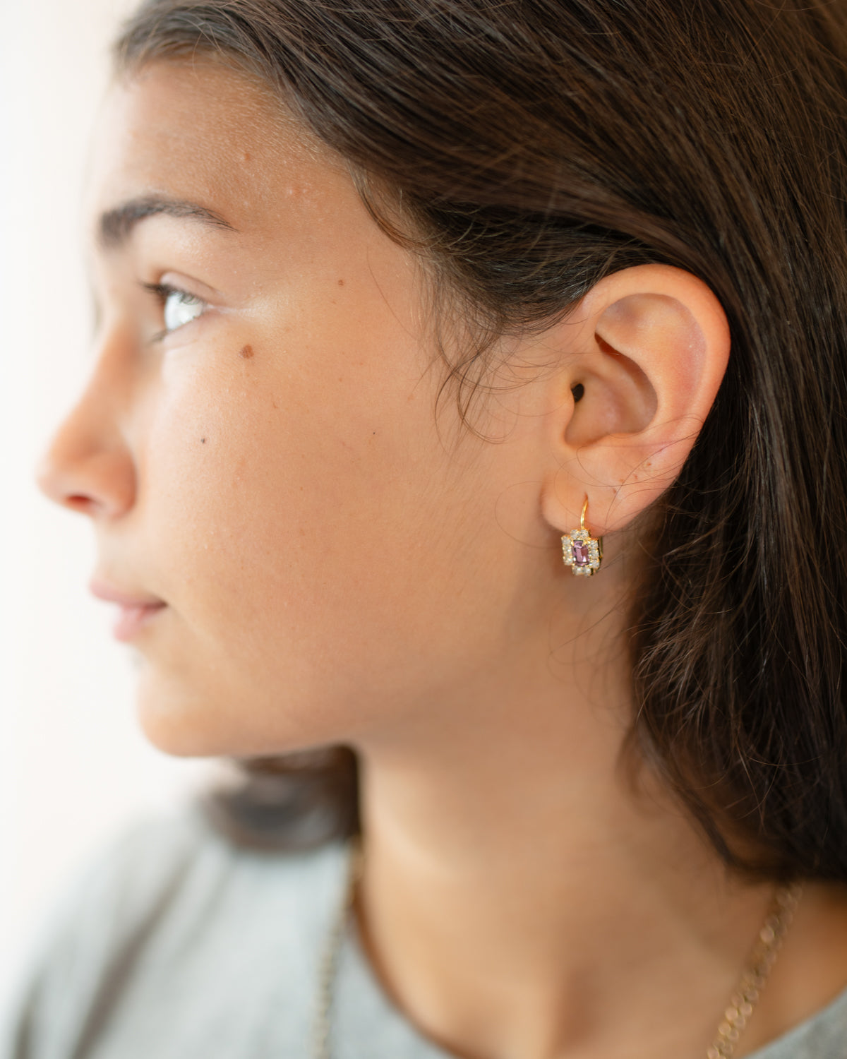 Side profile of a girl wearing a small vintage leverback earring with an amethyst-colored stone