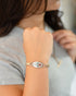 Woman in a gray tee wearing the Winter Bloom enameled flower watch band bracelet