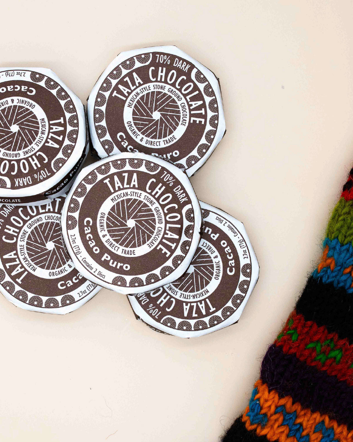 Taza Cacao Puro 70% dark chocolate discs in brown and white wrappers, stacked loosely