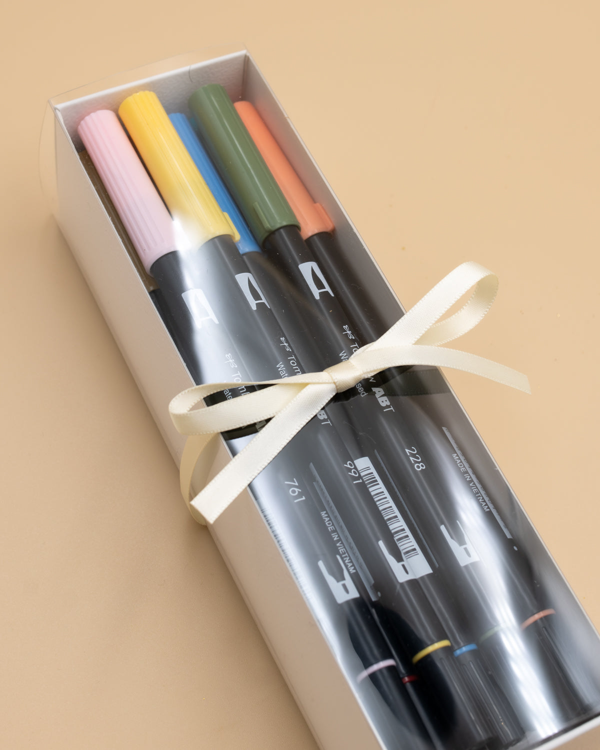 Boxed set of 12 Tombow dual brush pens in pink, yellow, blue and green, tied with a cream ribbon.