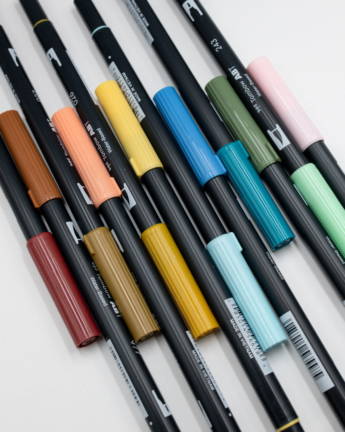 Twelve Tombow ABT dual brush pens laid out in rust, ochre, sage, sky blue and pale pink.