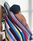 Person wrapped in a colorful terry cloth stretchy striped towel.