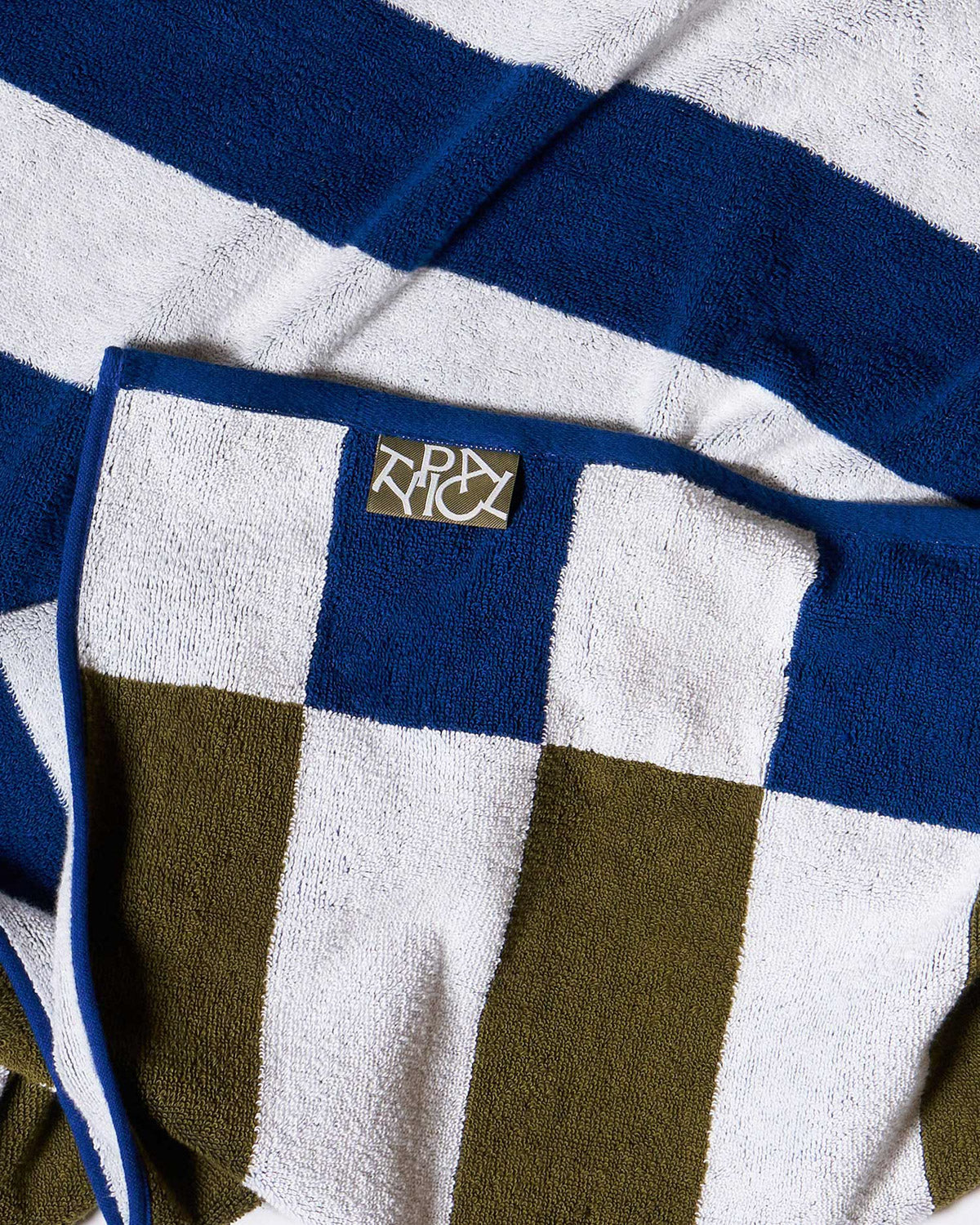 Close-up of a striped stretchy bath towel with the brand logo, Typical. 