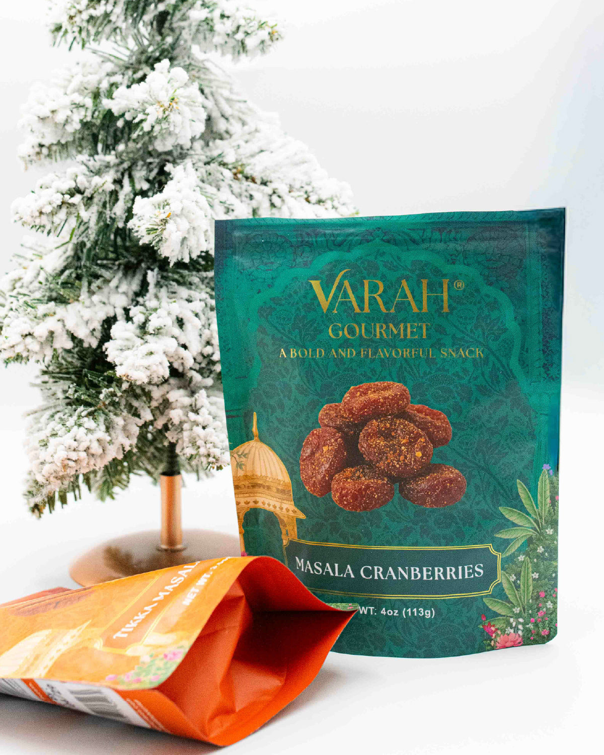 Varah Gourmet Masala Cranberries pouch in teal beside a snowy mini tree