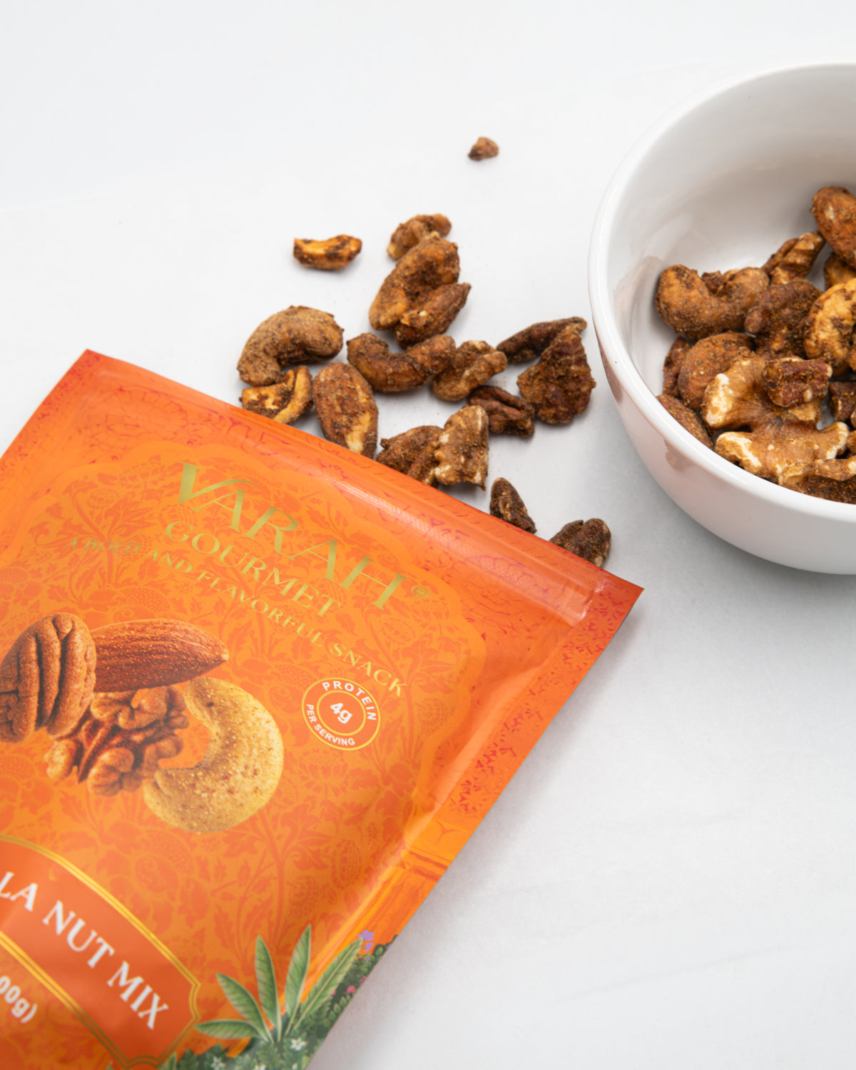 Tikka masala spiced pecans and cashews spilling from the Varah pouch beside a bowl