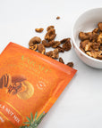 Tikka masala spiced pecans and cashews spilling from the Varah pouch beside a bowl