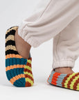 Side view of the striped knit house slippers worn with cream sweatpants