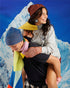 Two teens in Verloop grid knit beanies and colorful scarves in front of a snowy mountain backdrop
