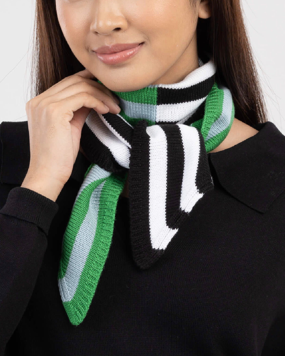 Model wearing the Verloop mini ribbon scarf in black, white and green stripes, tied at the neck