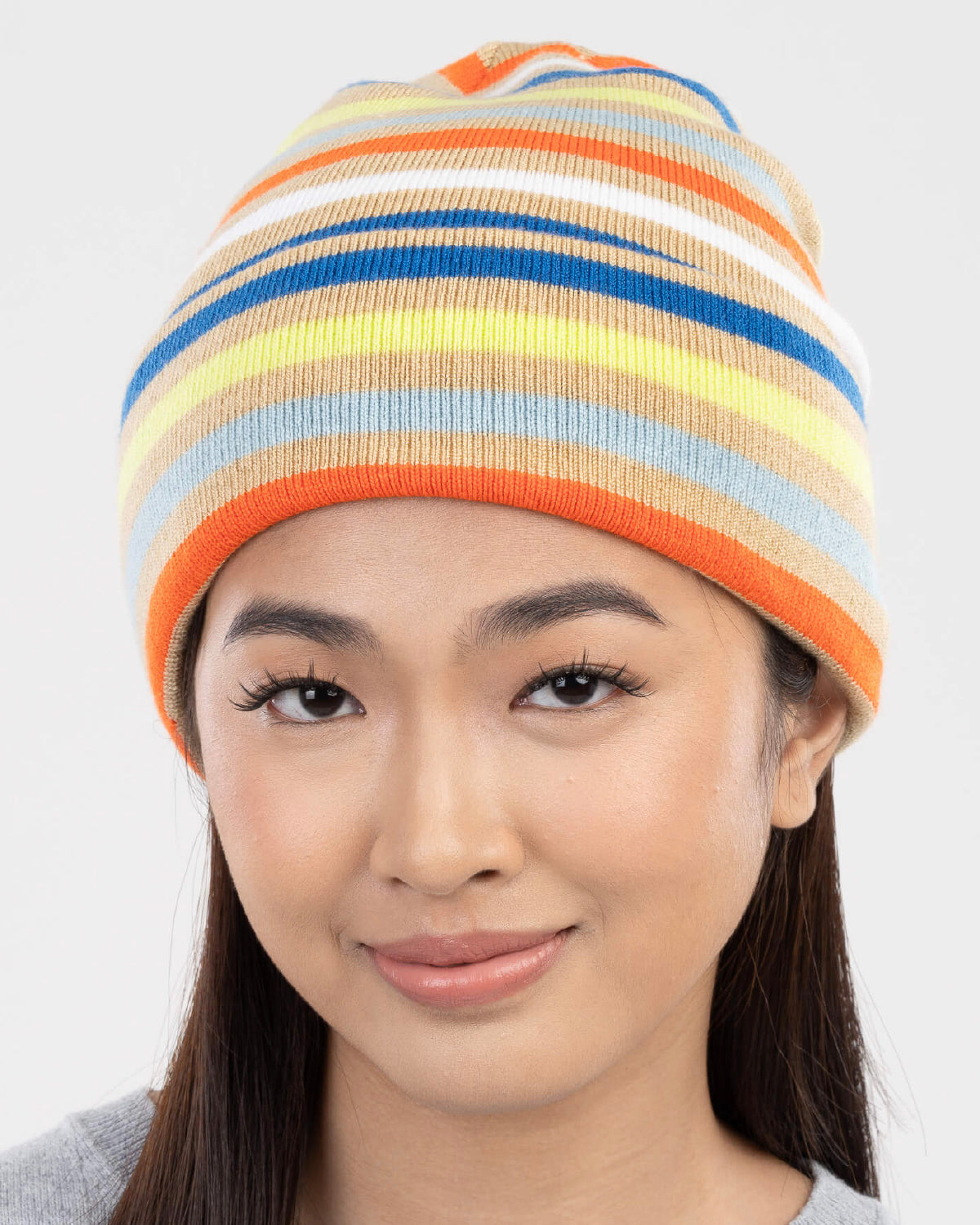 Smiling model wearing the Verloop striped knit beanie in orange, blue and yellow