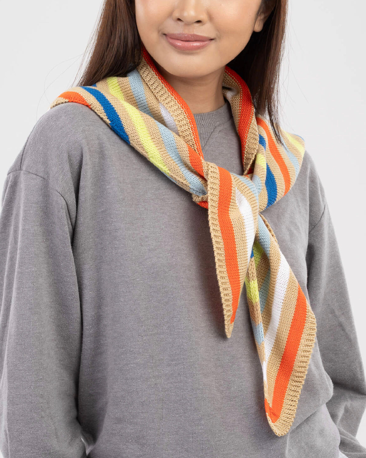 Model in a gray sweatshirt wearing the striped triangle scarf knotted at the side