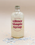 Glitter Simple Syrup bottle with pink lettering on scattered star confetti