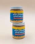 Two stacked jars of Hot Honey Sprinkles with bright blue and yellow flame labels