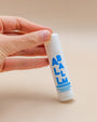 Hand holding a Zizia All Balm multi-balm stick in white with bold blue lettering