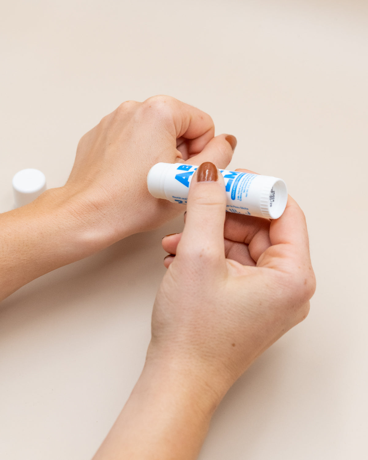 Hands applying the All Balm stick to dry cuticles