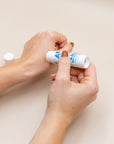 Hands applying the All Balm stick to dry cuticles