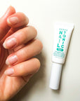Hand with bare, healthy nails holding a tube of Zizia Nail Tonic