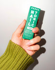 Hand in a green sweater holding the Zizia Nail Tonic box in green and white