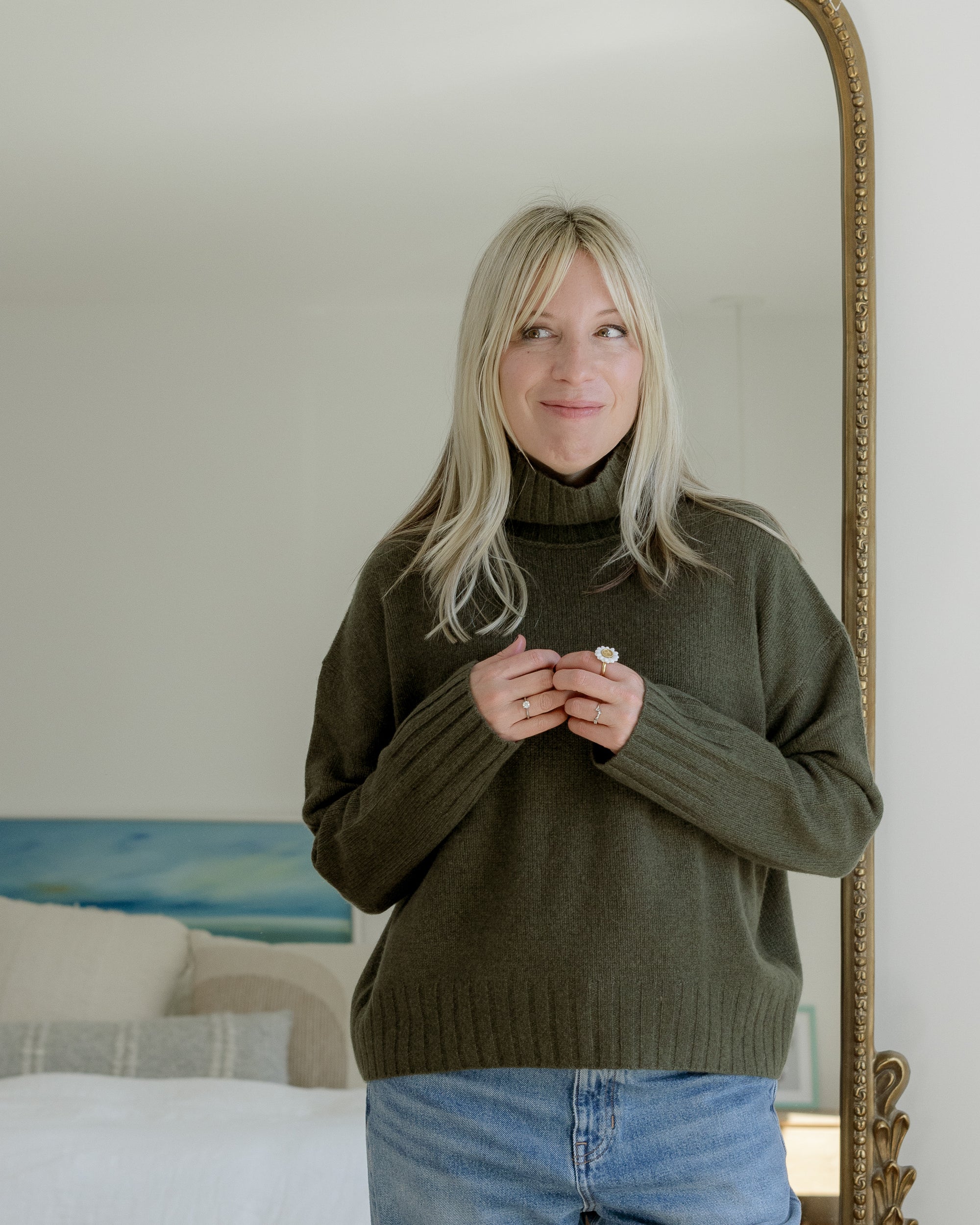 Woman wearing hand-painted daisy ring with green cashmere turtleneck — thoughtful small-business jewelry gift idea.