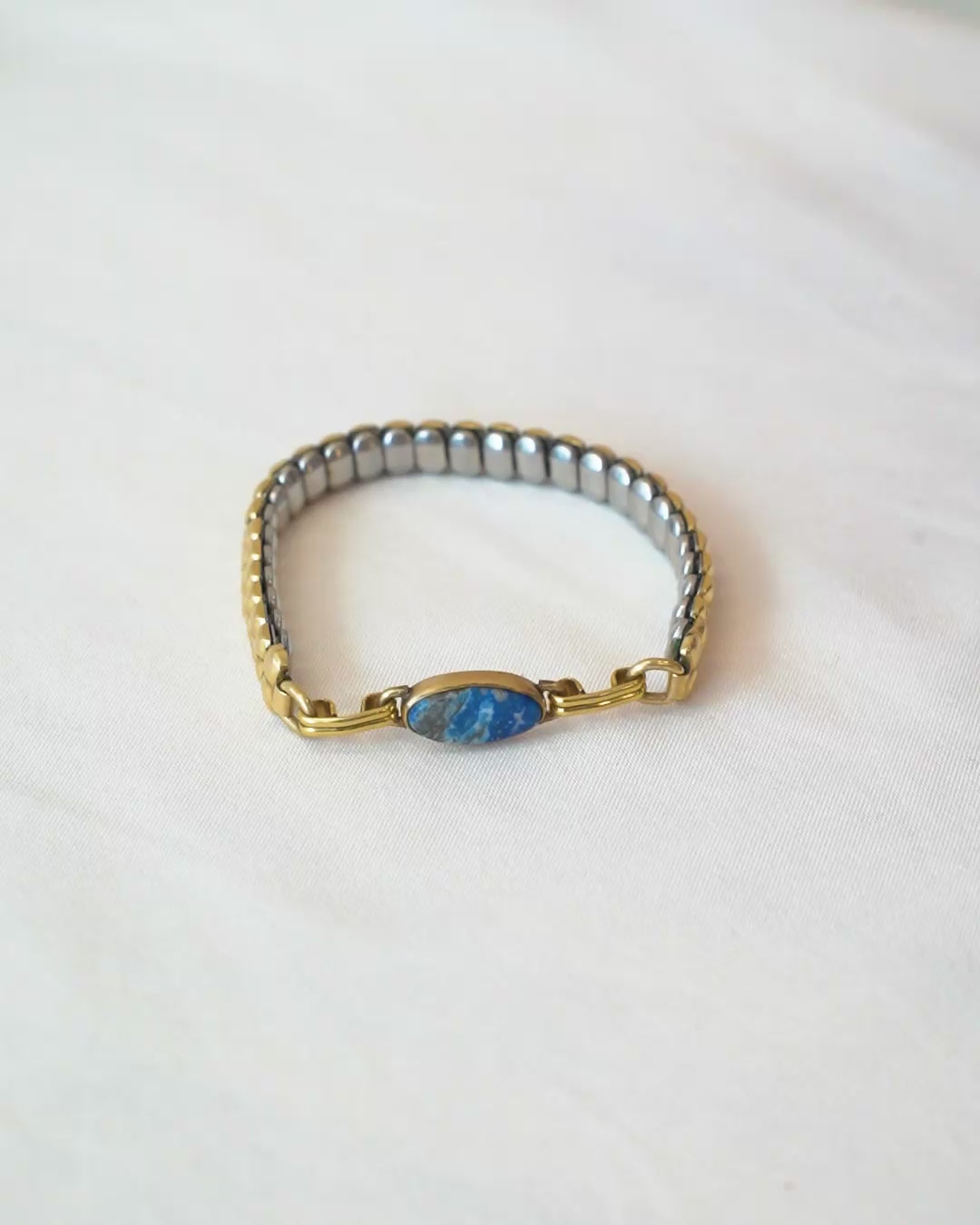 Person trying on a vintage bracelet with lapis stone on a white background