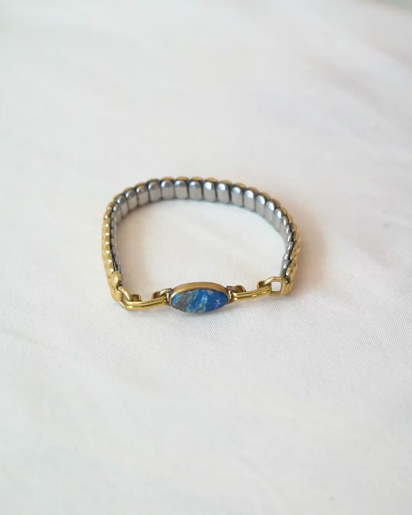 Person trying on a vintage bracelet with lapis stone on a white background
