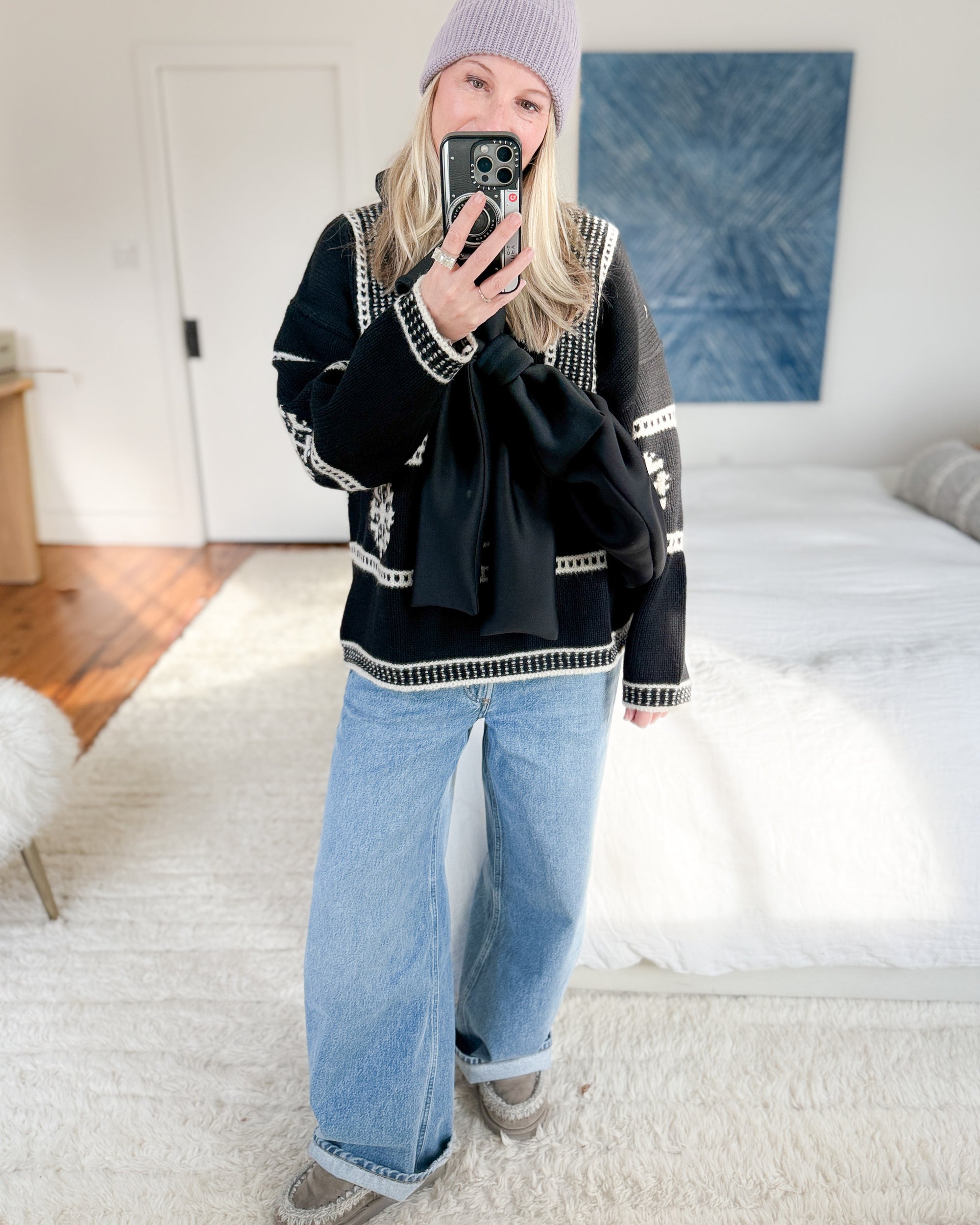 Cozy winter look featuring a black bow crossbody bag, wide-leg jeans, and a beanie.